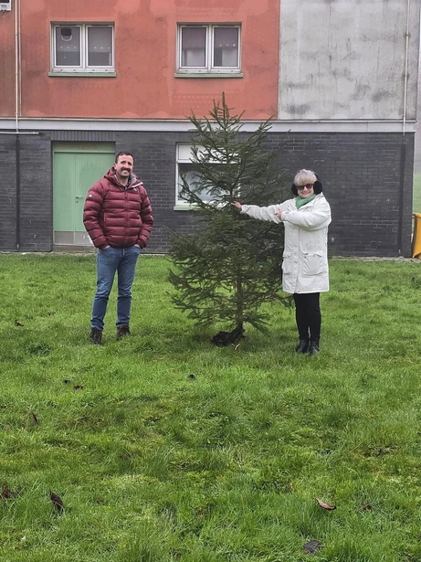 Elaine from Westbridgend TRA and Patrick from Greenspace planting a small Christmas tree.
