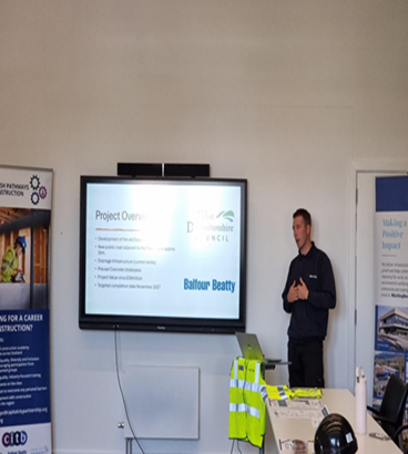 A group of smiling participants from the Pathways to Construction Programme standing together in front of a construction project.