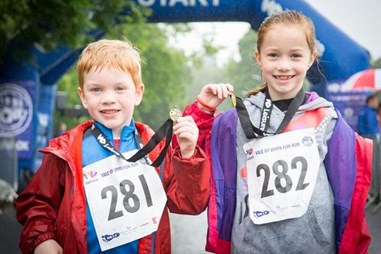 Boy and girl holding up medals after run