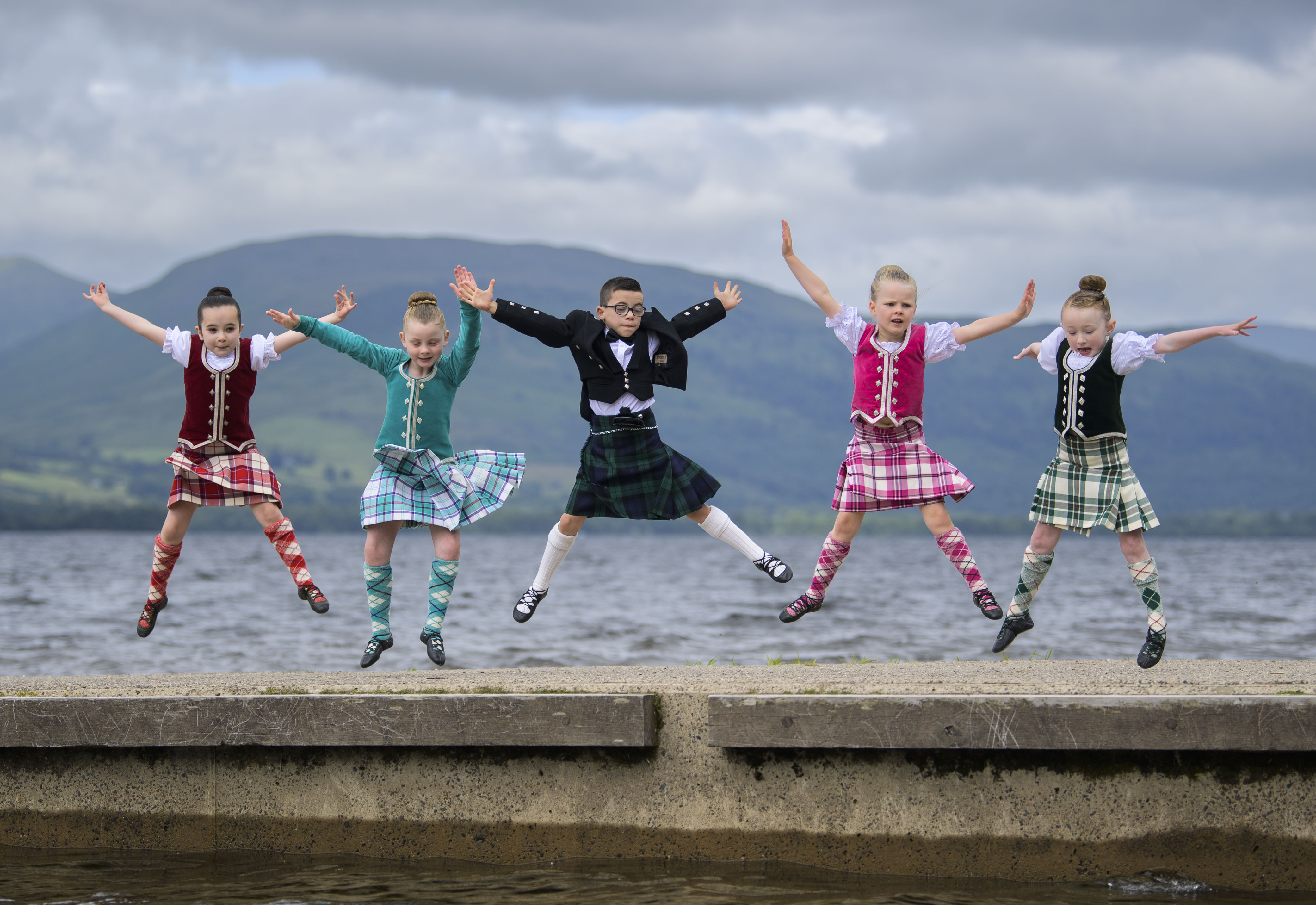 Young people in highland dress jumping for joy