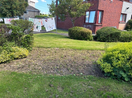 Volunteers in safety gear using a power washer to clean paving stones in the Women's Aid garden.