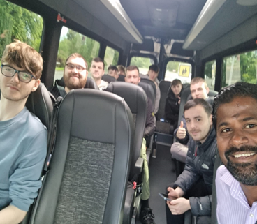 Two participants in high-vis vests and hard hats receiving practical instruction from a site professional on a construction site.