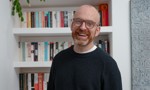 Photo of Matt Haig standing in front of a bookcase 