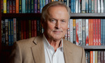 John Grisham standing in front of a bookcase