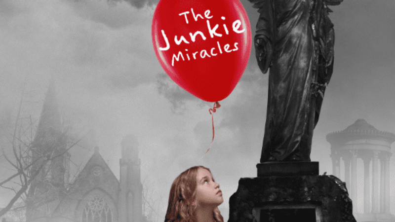 Little girl in pink dress looking up at red balloon