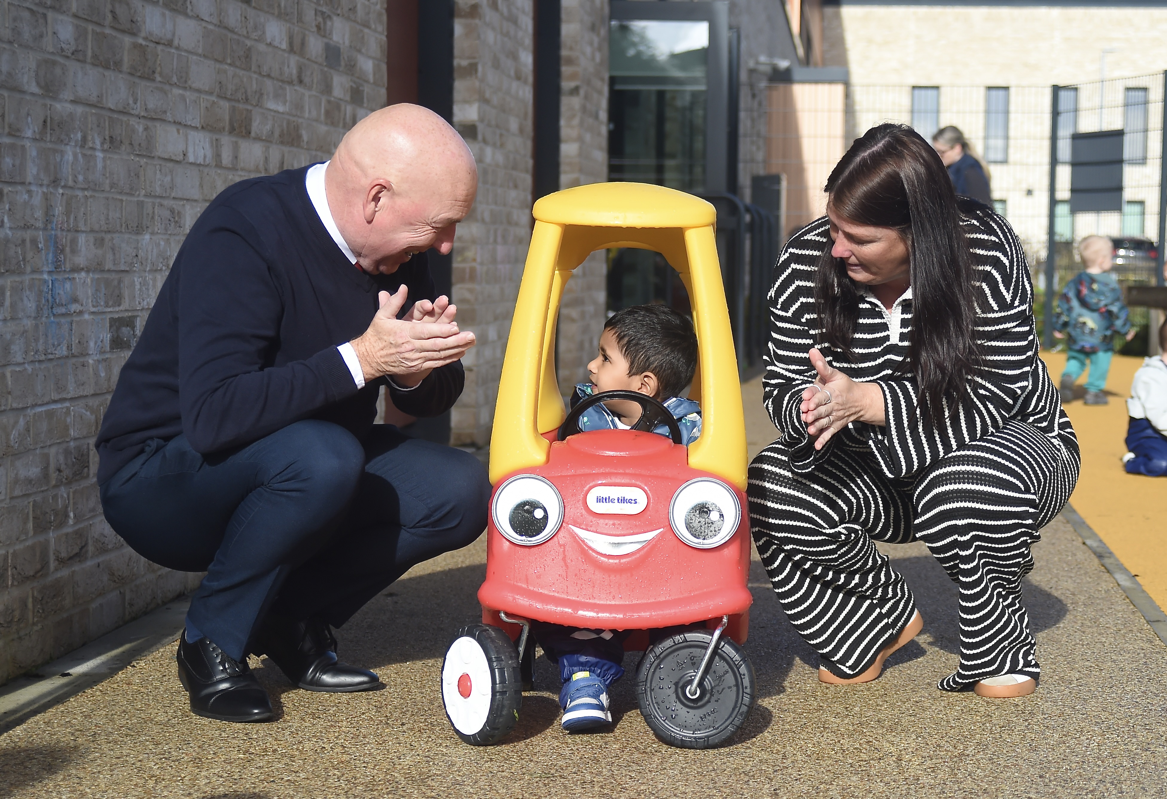 Councillor John Millar and Councillor Michelle McGinty alongside a child in a toy car